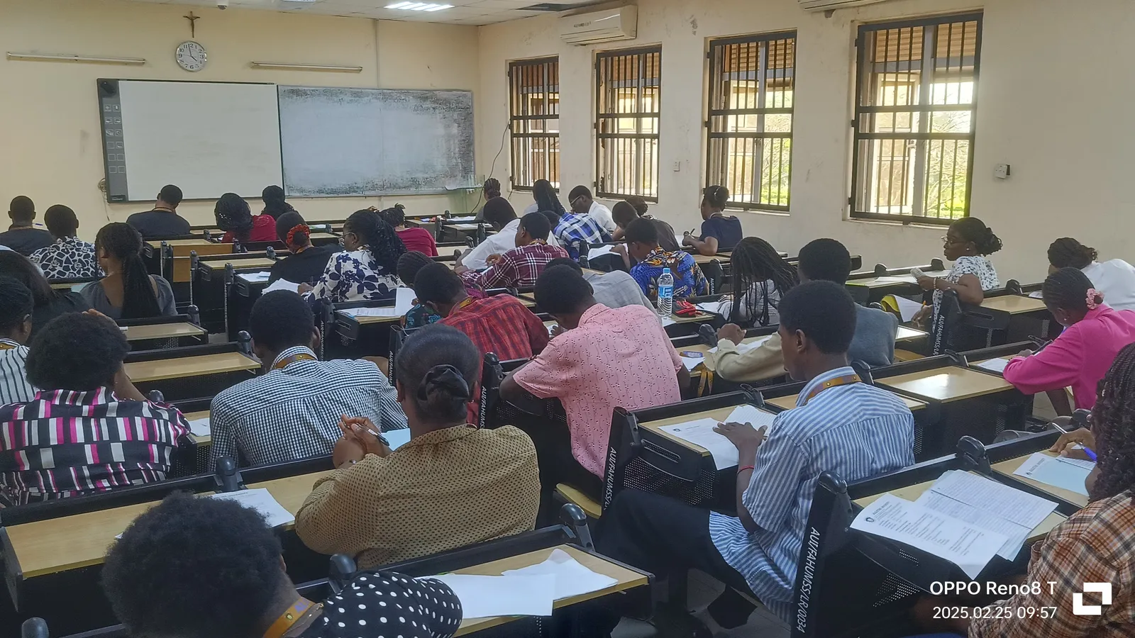 Students seen from behind writing an exam at closely spaced desks