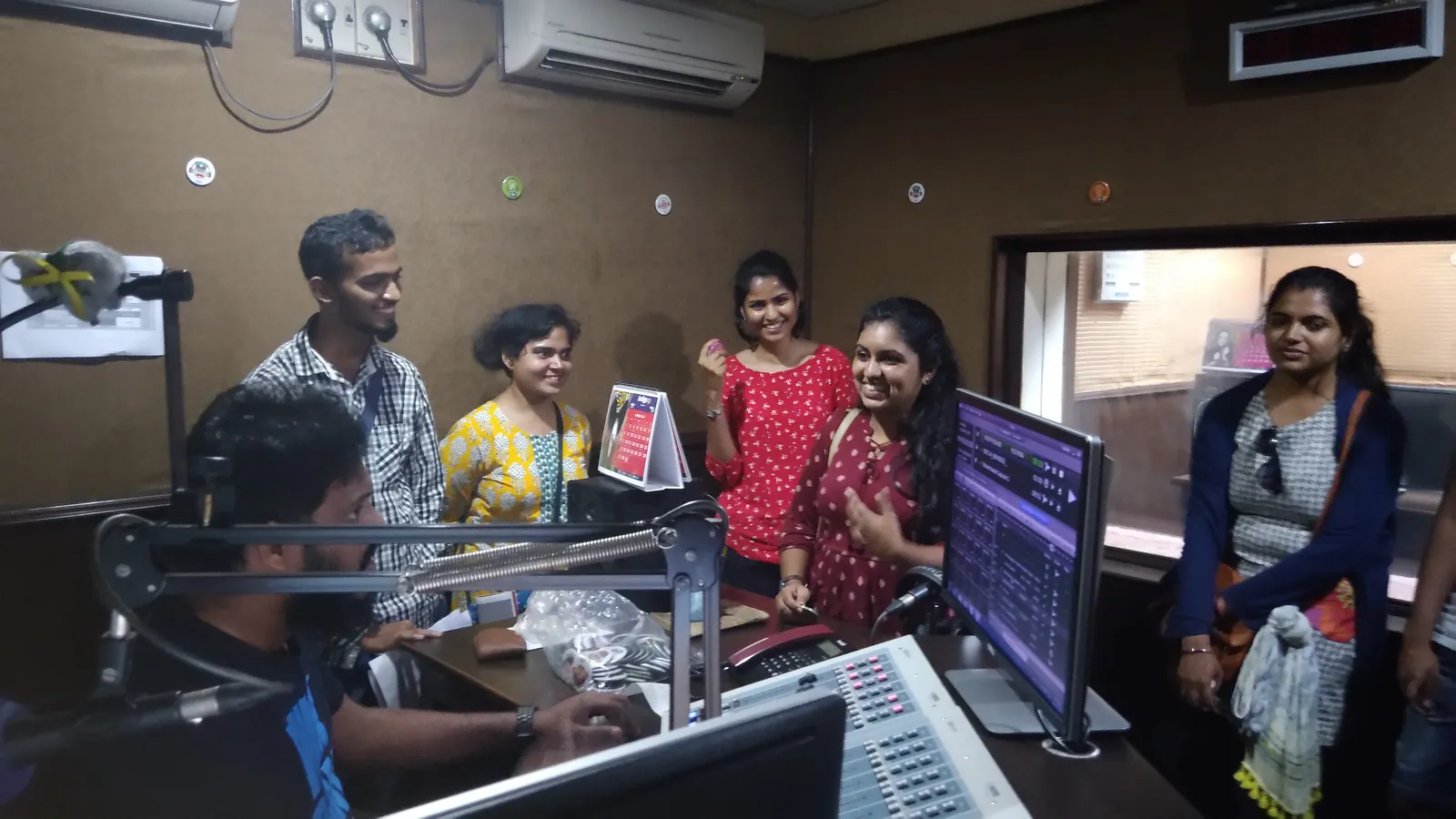 Students watch a radio presenter at the mixing desk during a studio visit