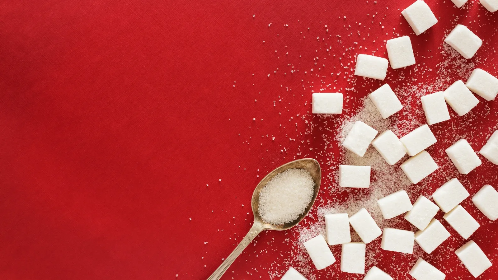 Sugar cubes and a spoon on red cloth
