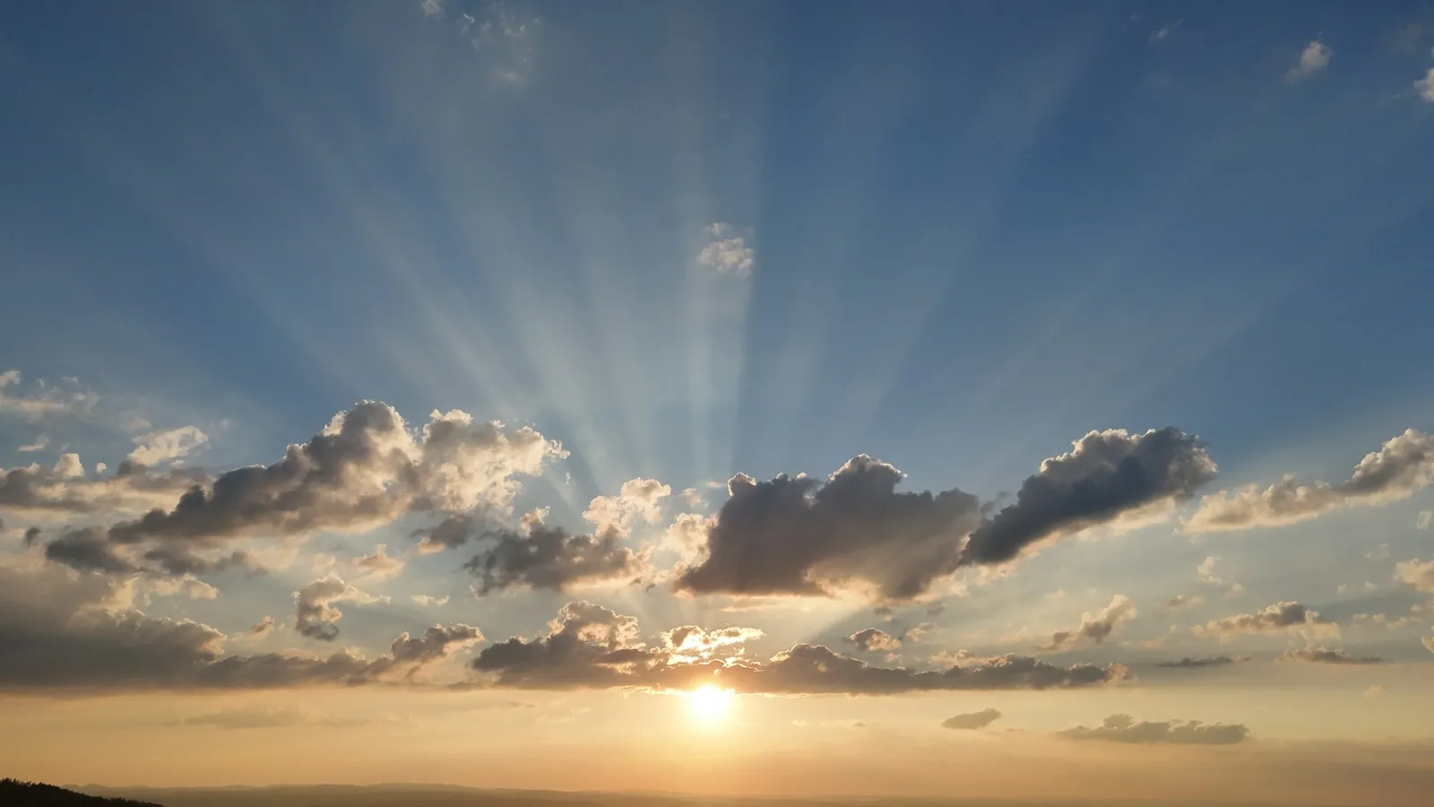 Sun rays streaming through clouds over the horizon