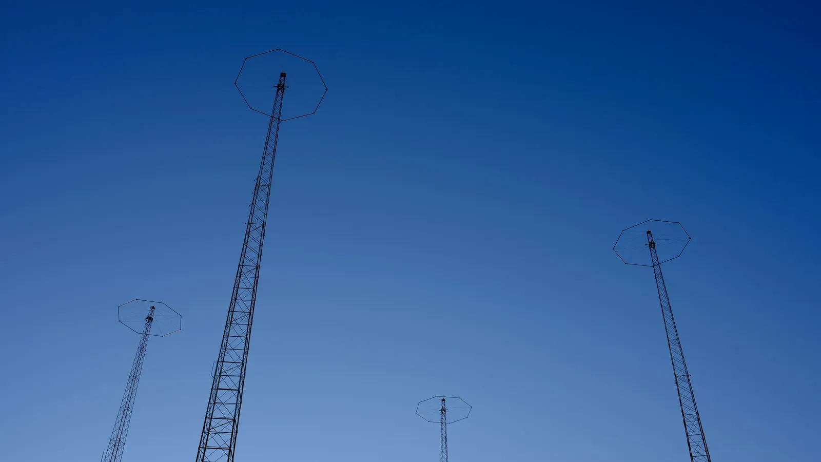 Tall radio masts against a deep blue sky