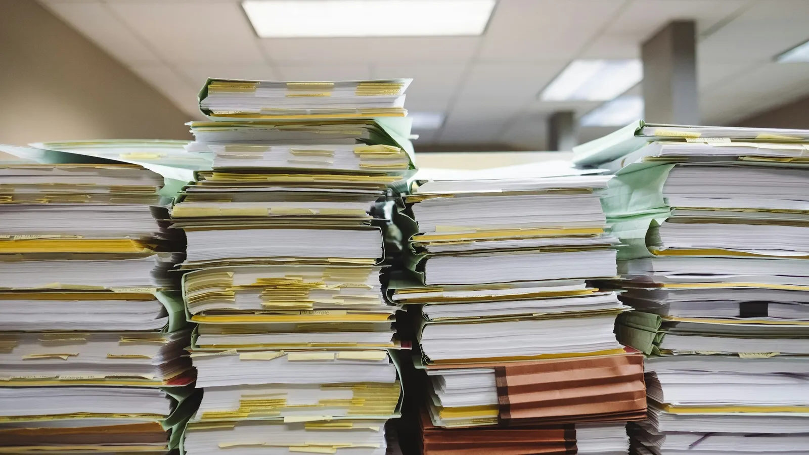 Tall stacks of paper files on a desk