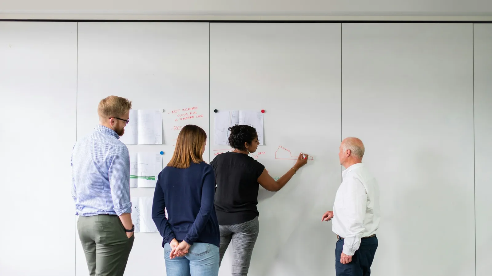 Team of people working together at a whiteboard