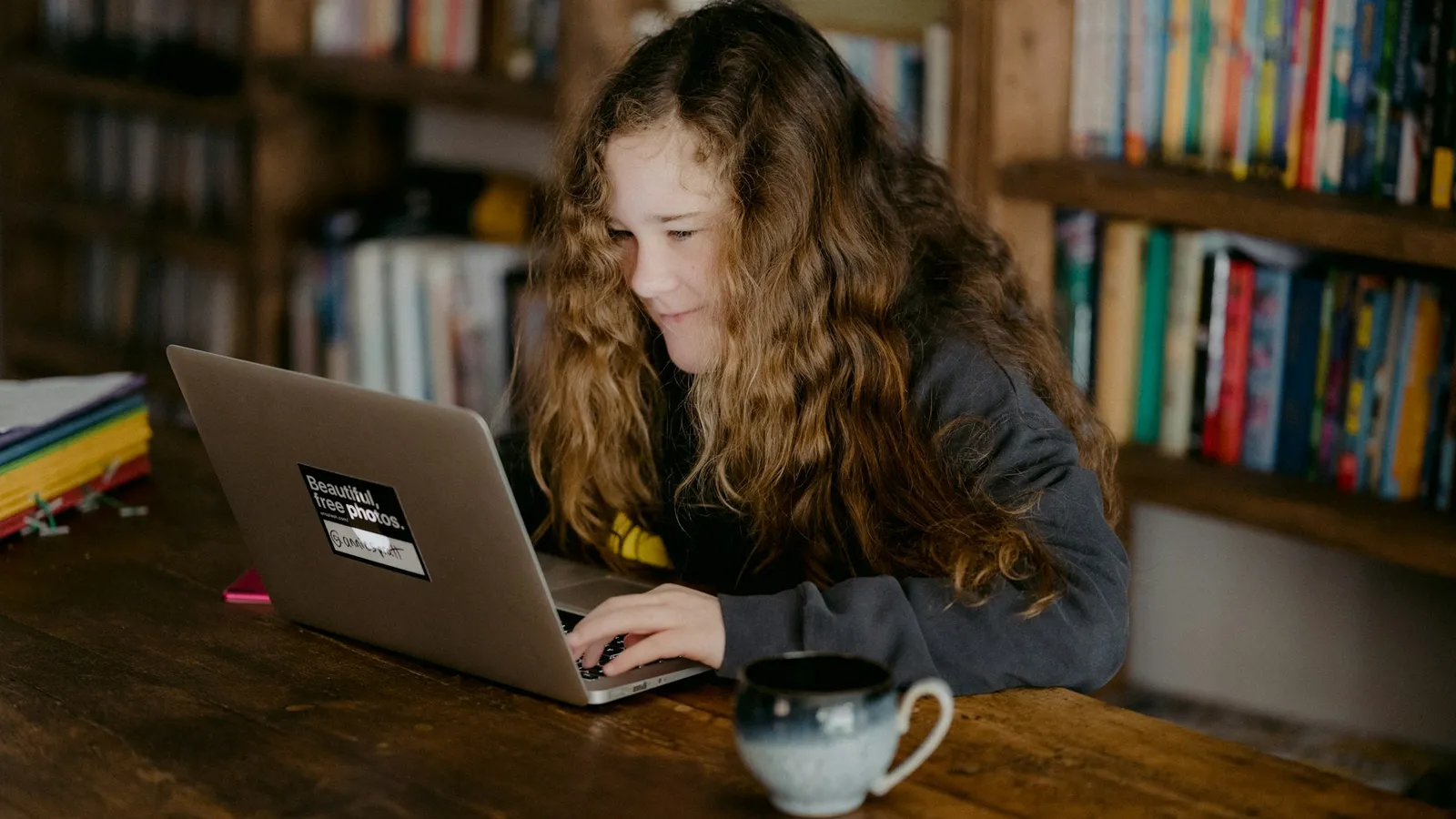 Teenage girl studying on a laptop at home
