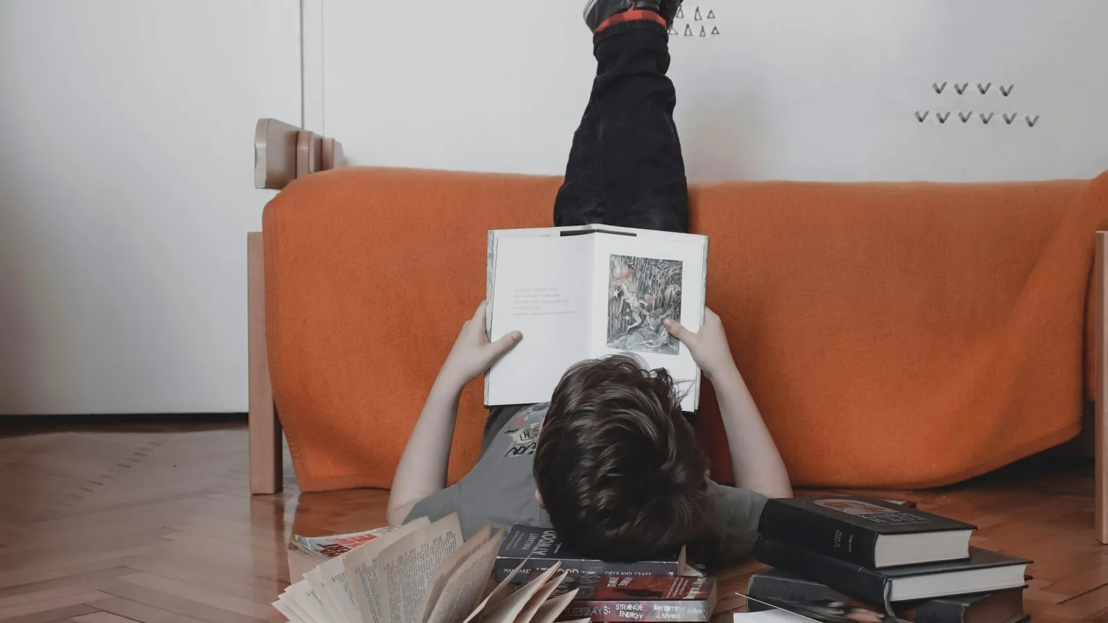 Teenager lying on a sofa reading a book