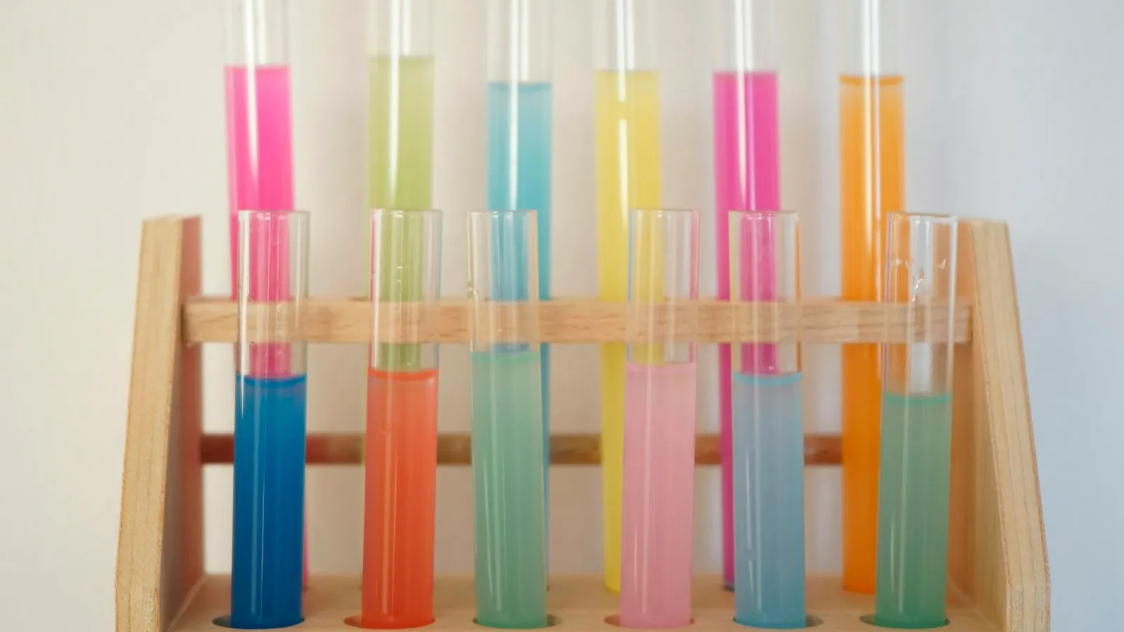 Test tubes of coloured liquid in a wooden rack