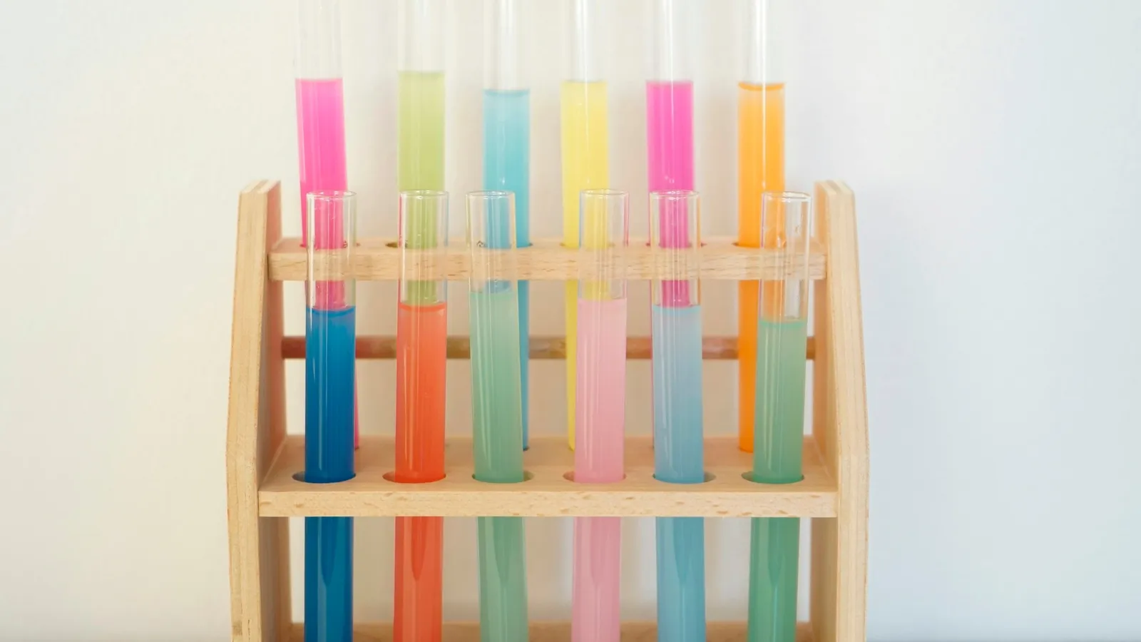 Test tubes of coloured liquids in a wooden rack