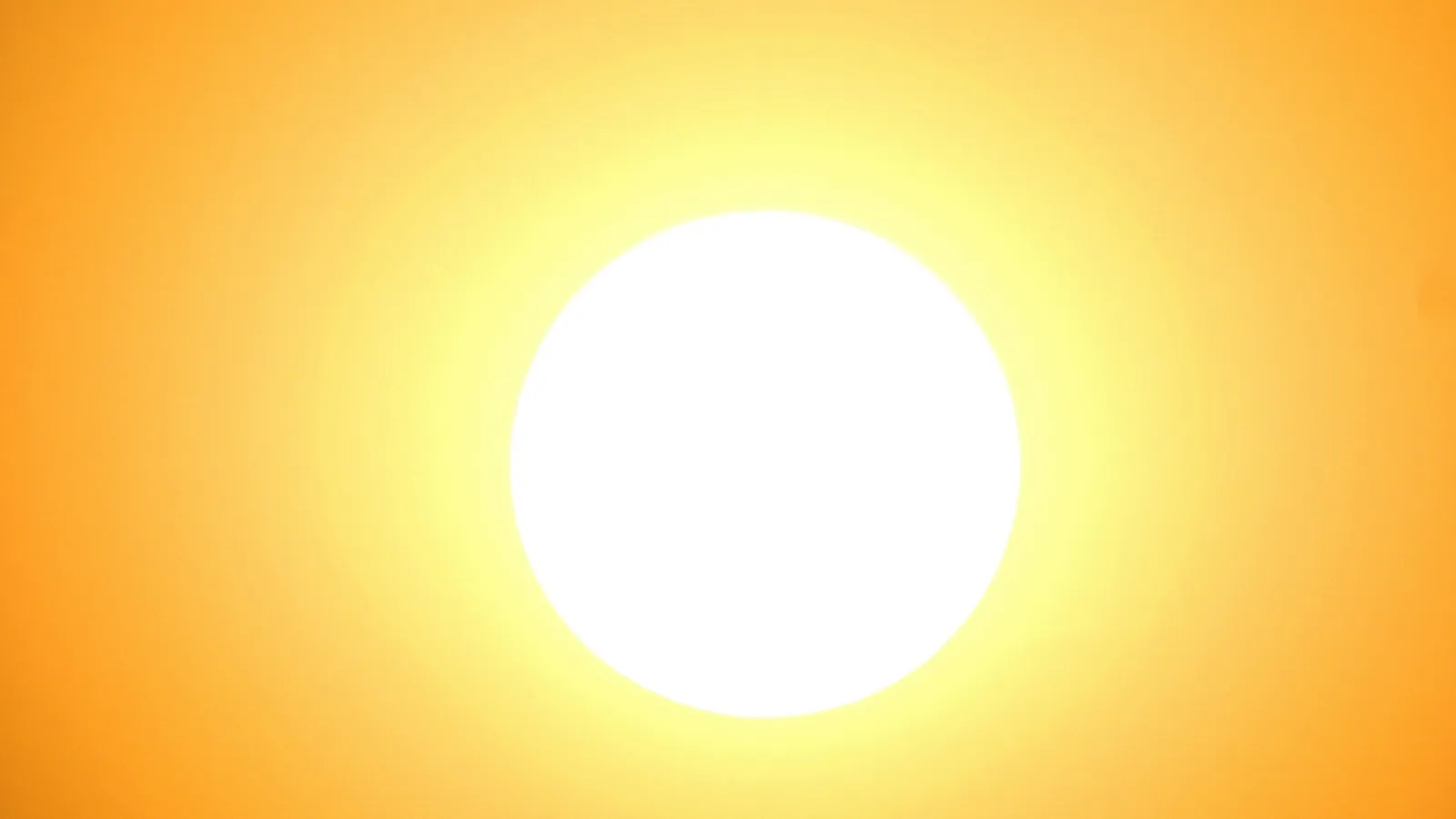 The bright disc of the Sun in a hazy orange sky