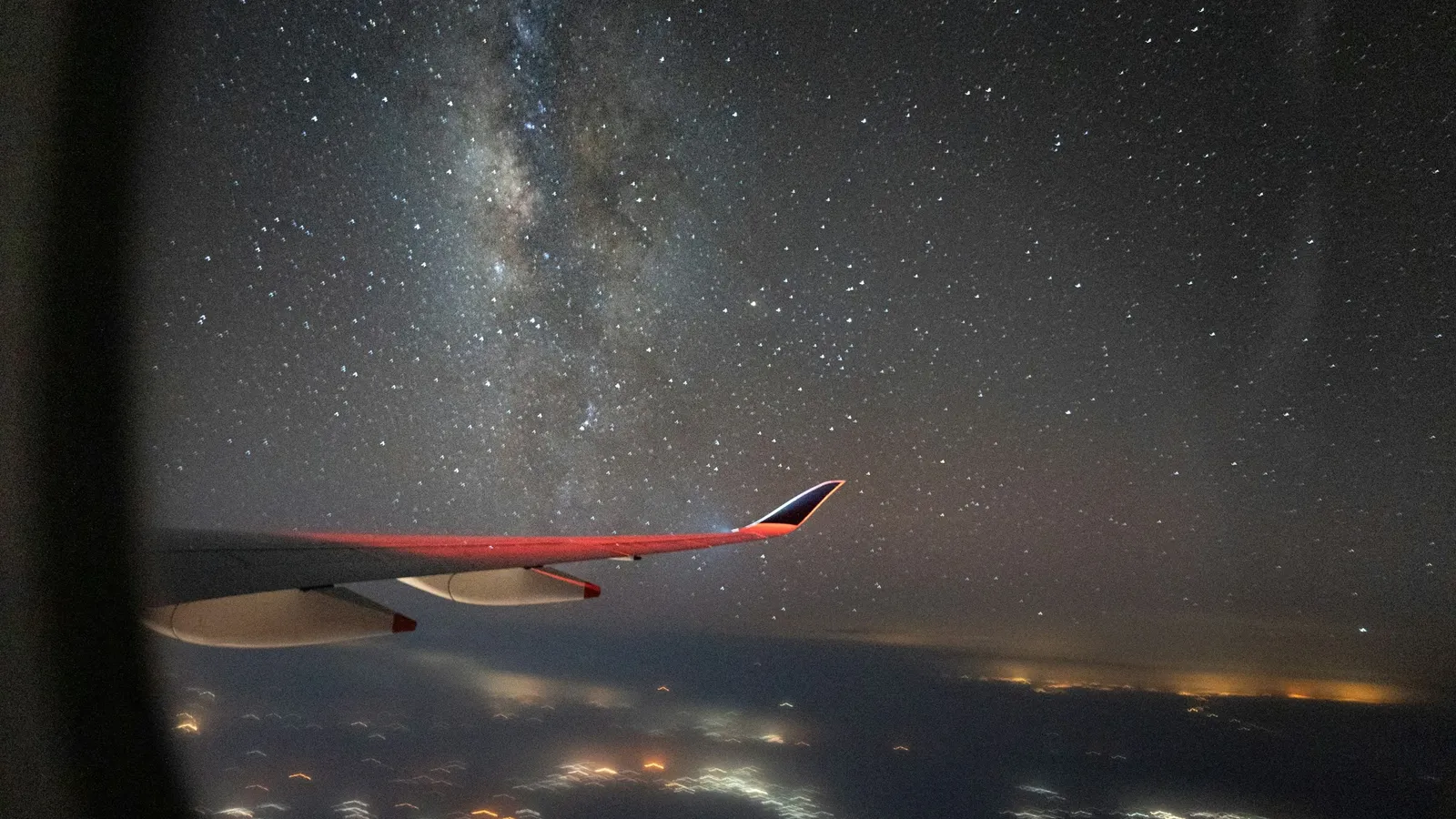 The night sky and lights below seen from an aircraft window