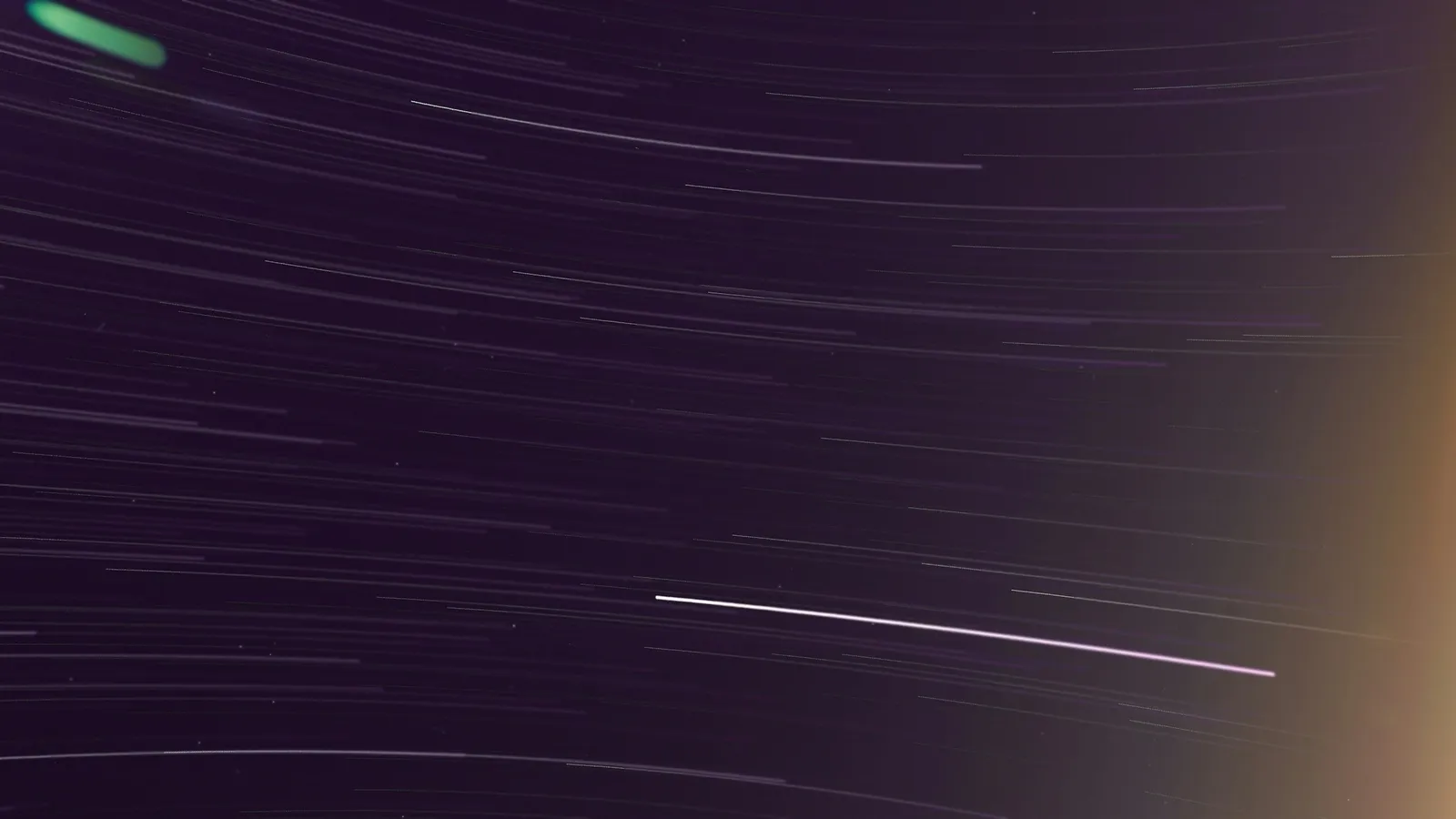 Thin streaks of light crossing a dark night sky