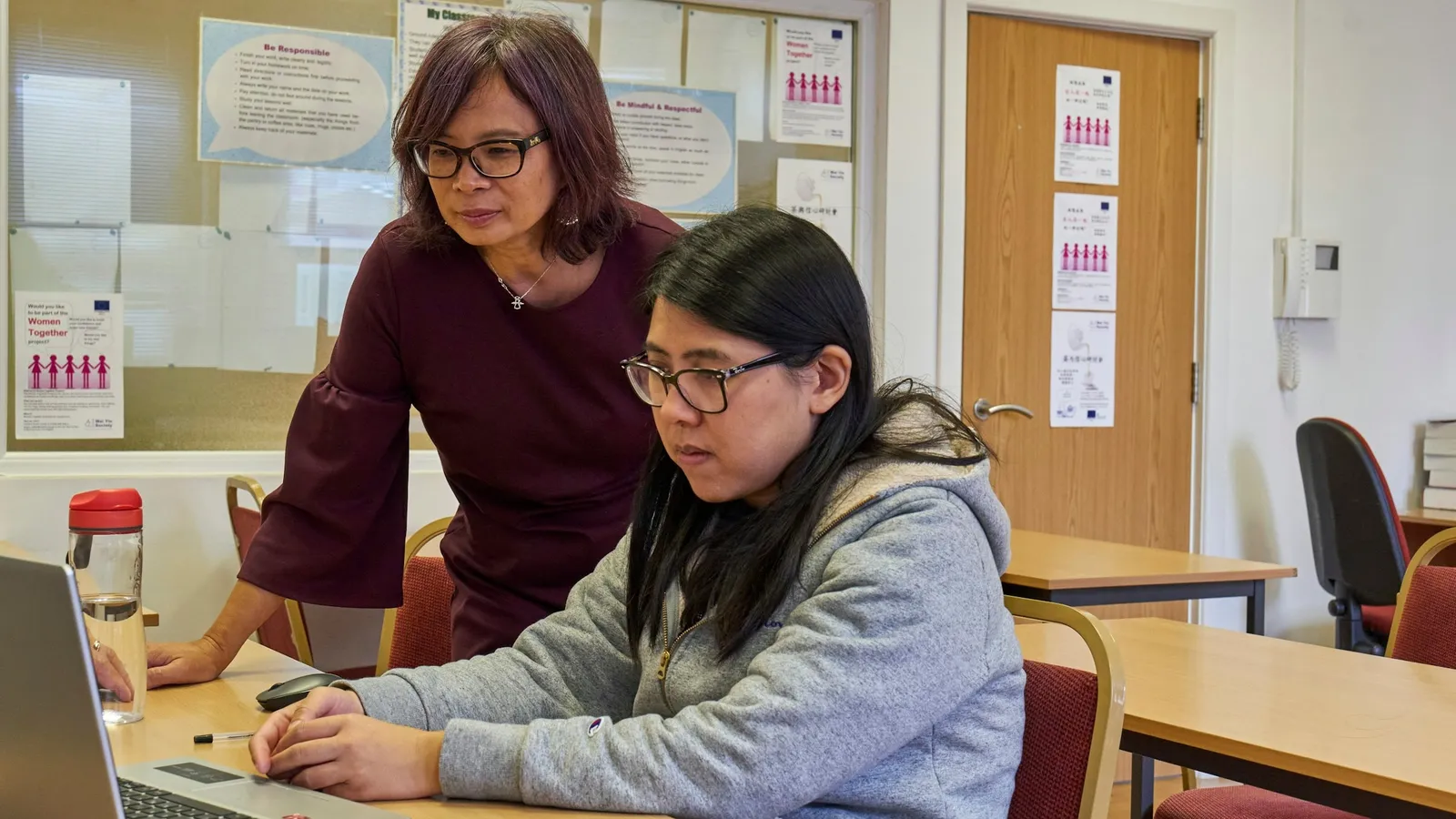 Tutor sitting with a student working at a desk