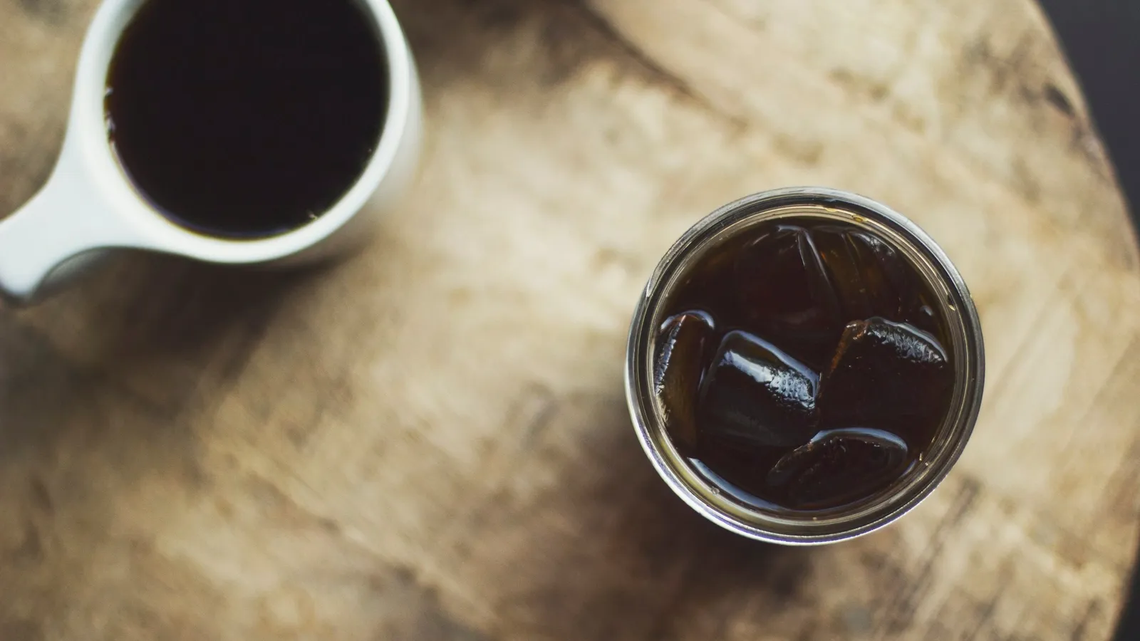 Two cups of coffee cooling on a wooden table