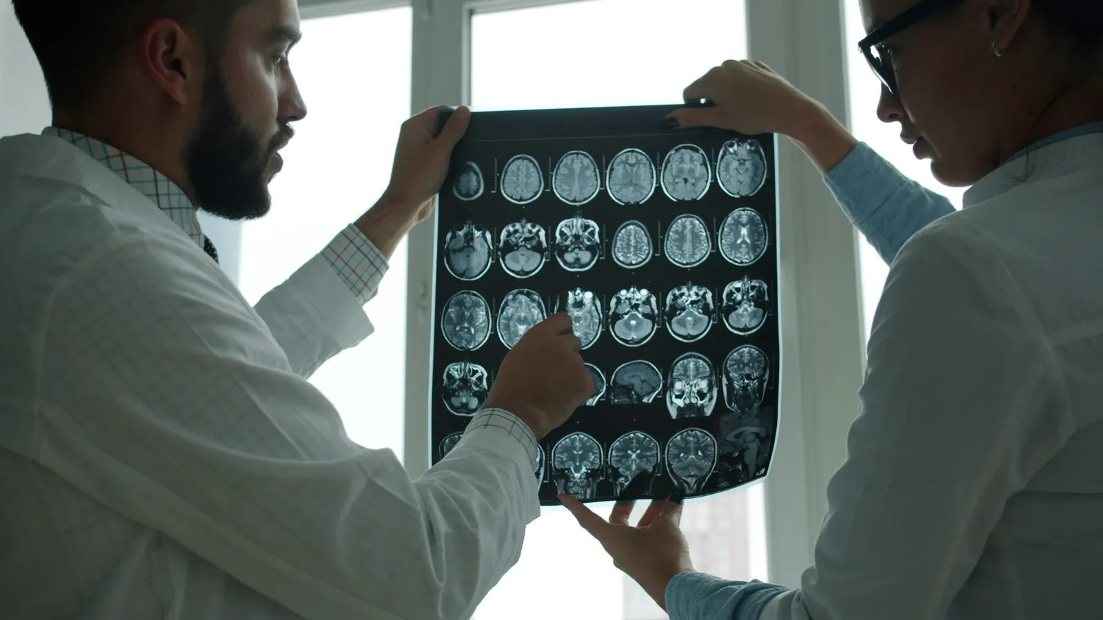Two doctors studying a sheet of scan images