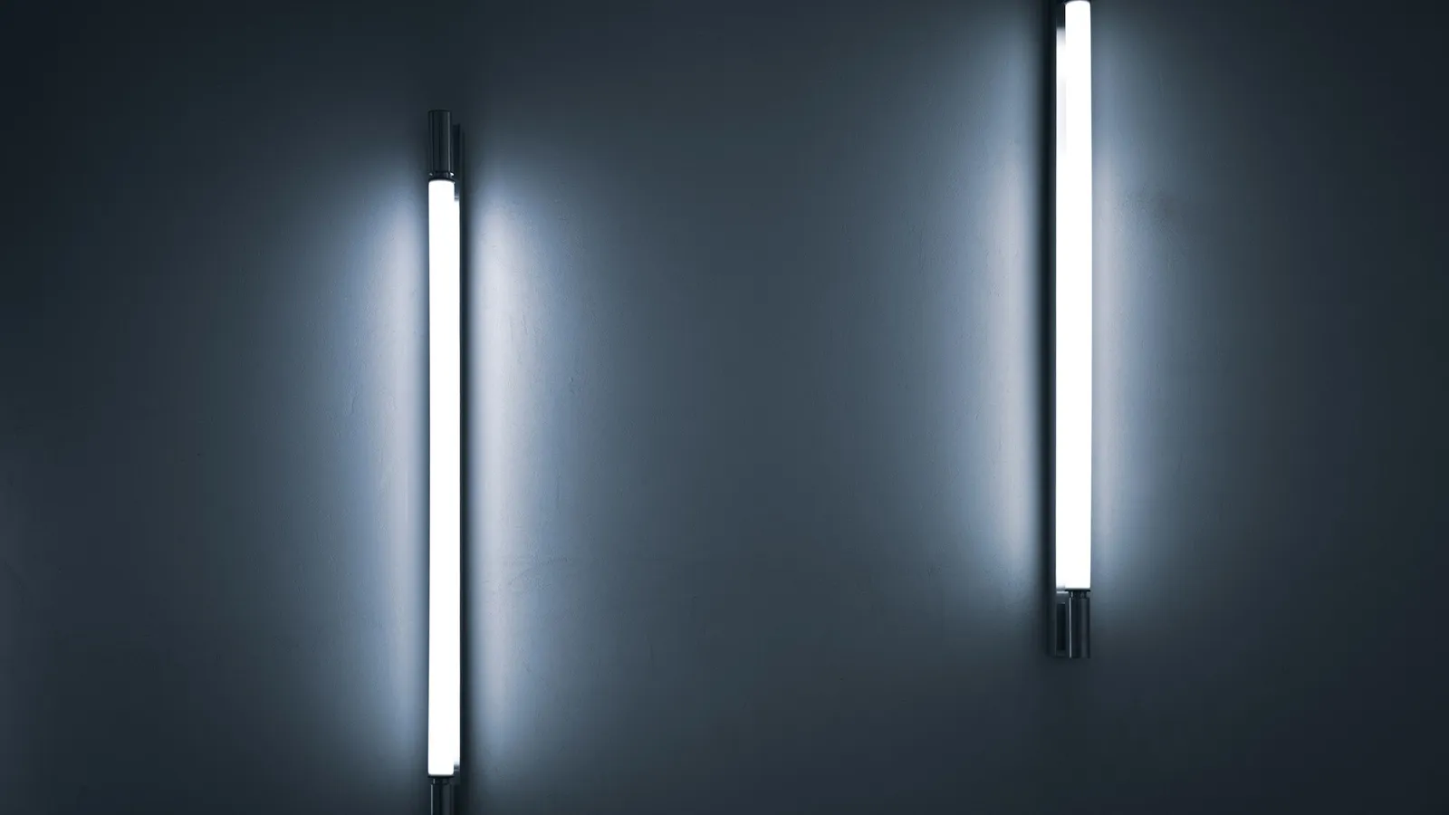Two glowing gas-discharge tubes on a wall