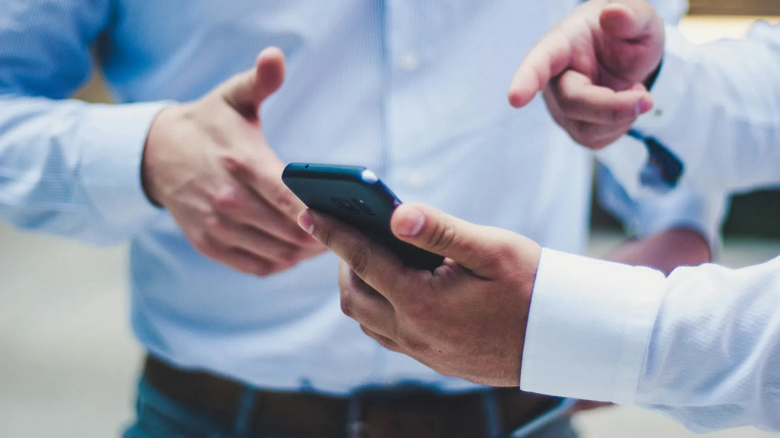 Two hands holding a smartphone, one pointing at the screen