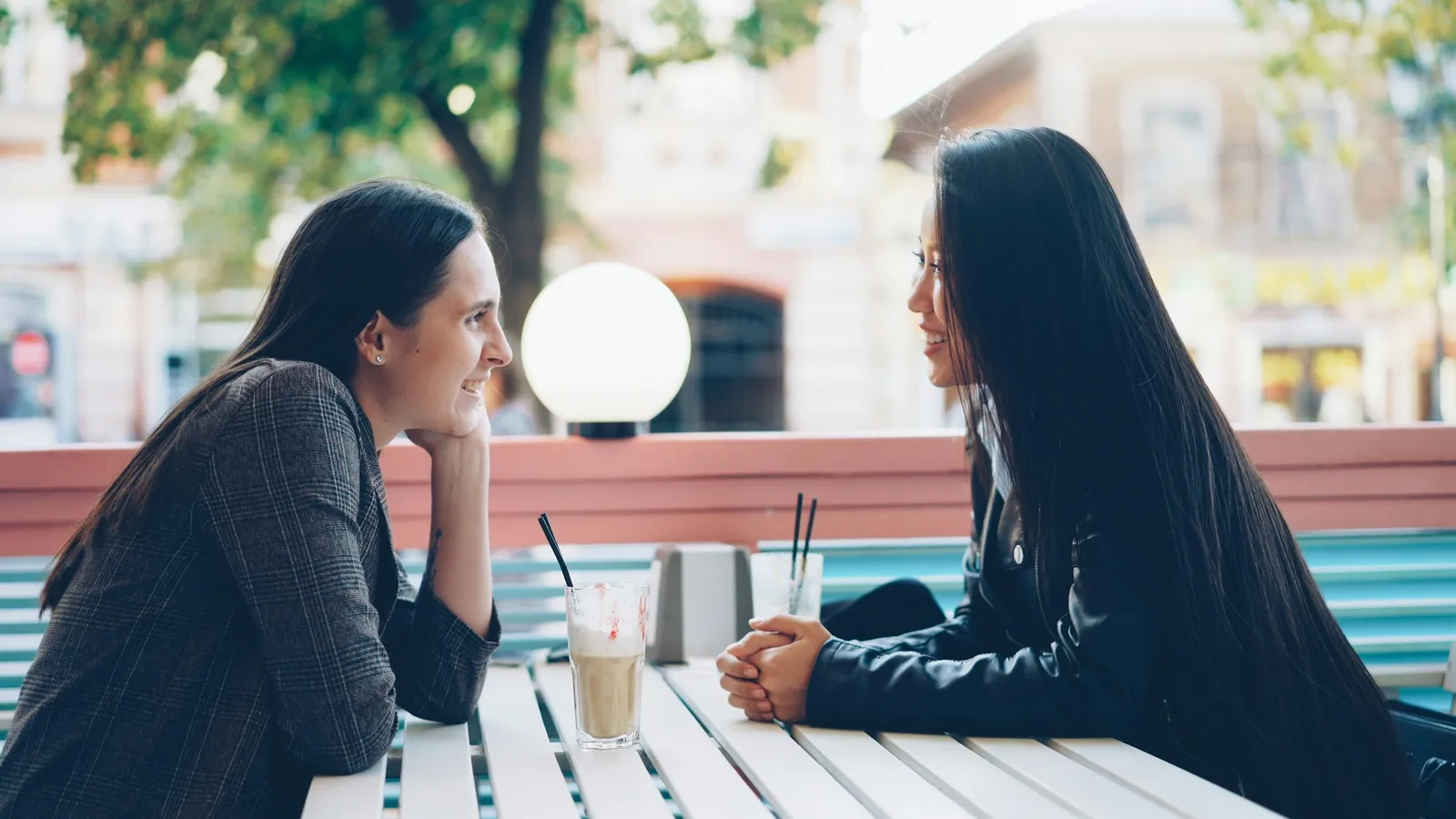 Two people talking at an outdoor cafe table