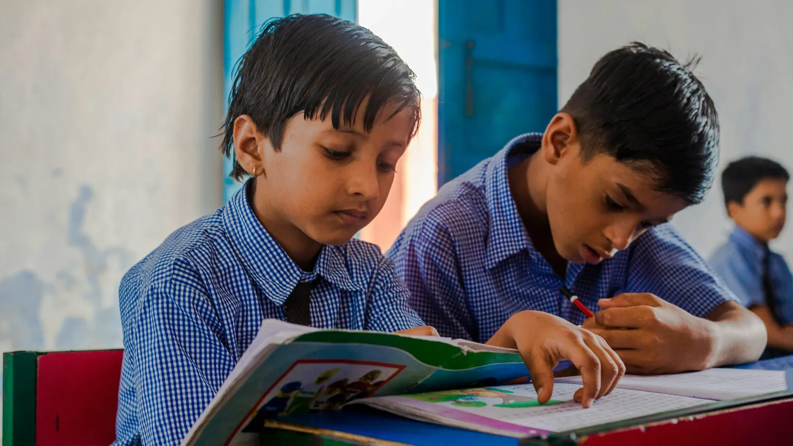 Two schoolboys reading together in a classroom