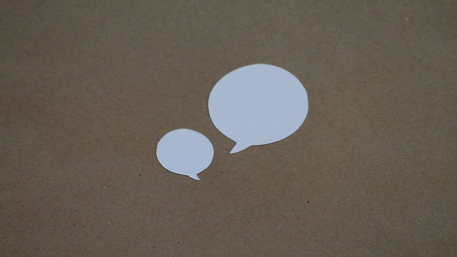 Two speech bubble shapes on a grey background
