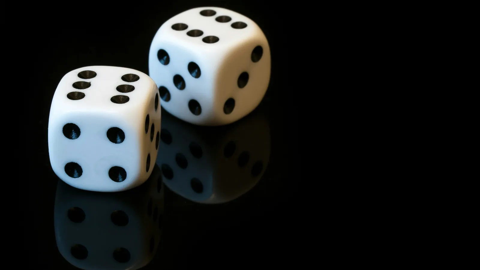 Two white dice on a black surface
