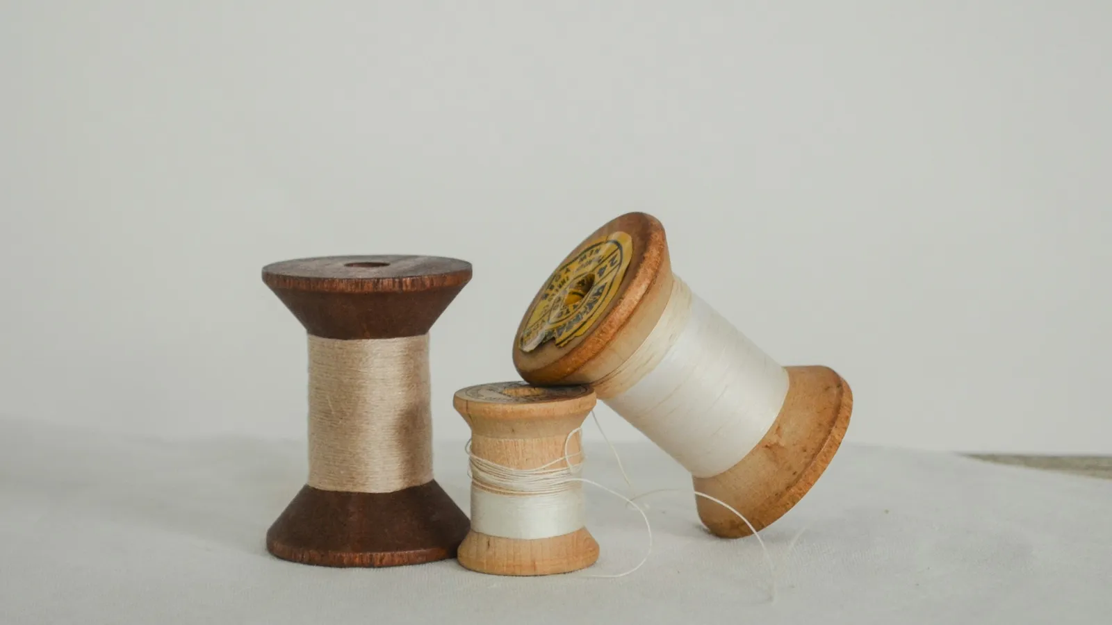 Two wooden spools of thread on a pale table
