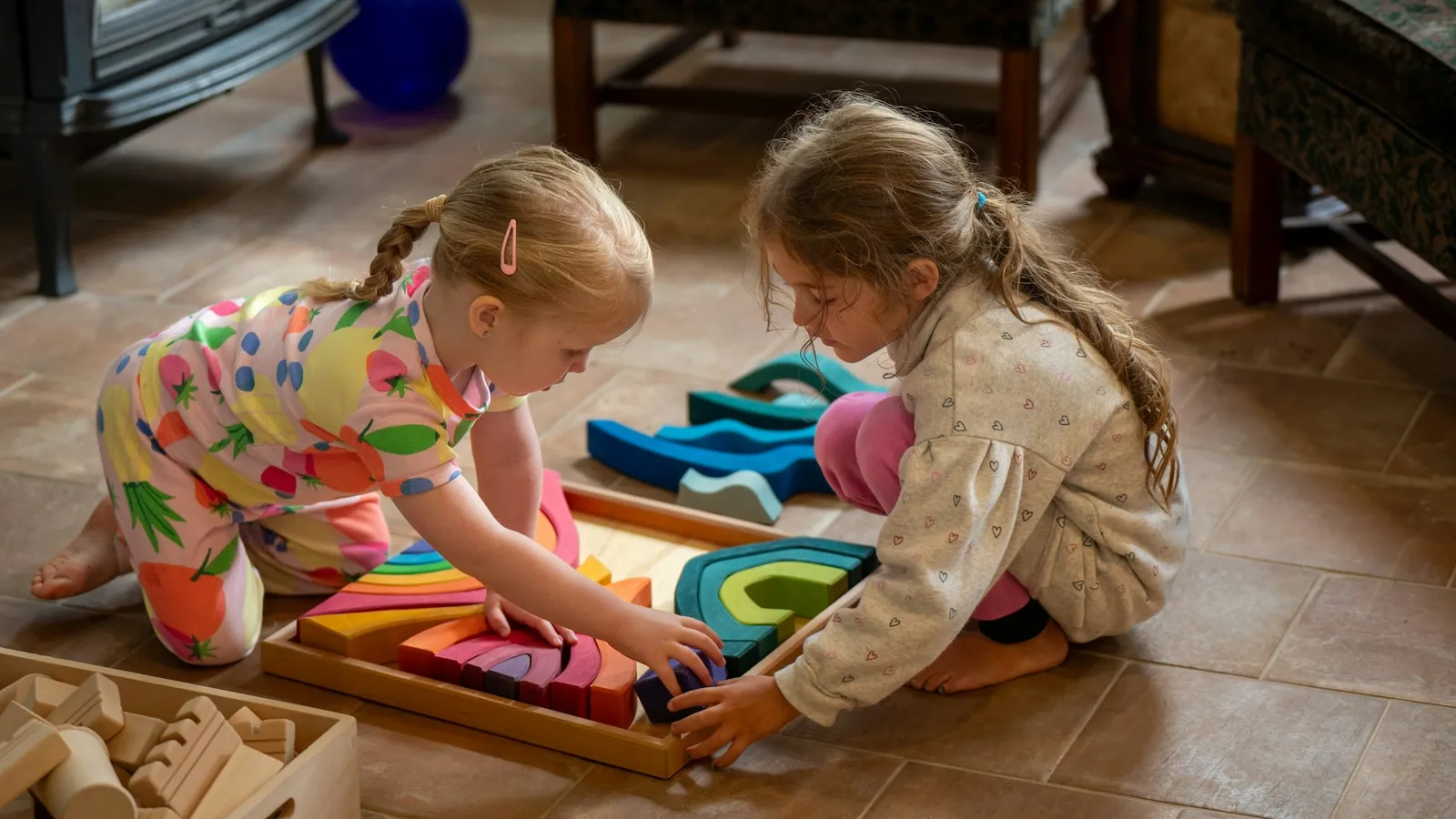Two young children playing with blocks on the floor