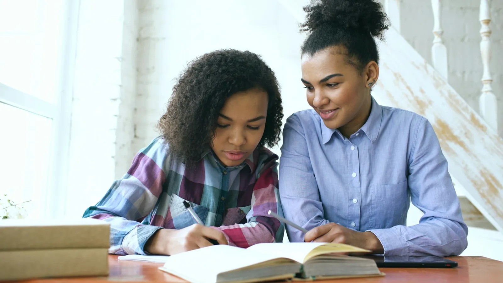 Two young women studying together over papers at a table