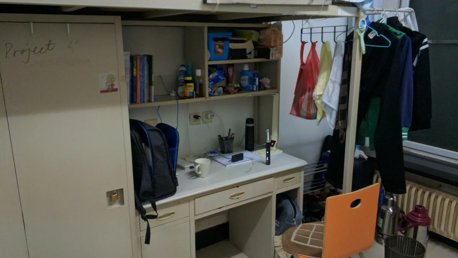 University dorm room with a study desk and chair beneath a loft bed