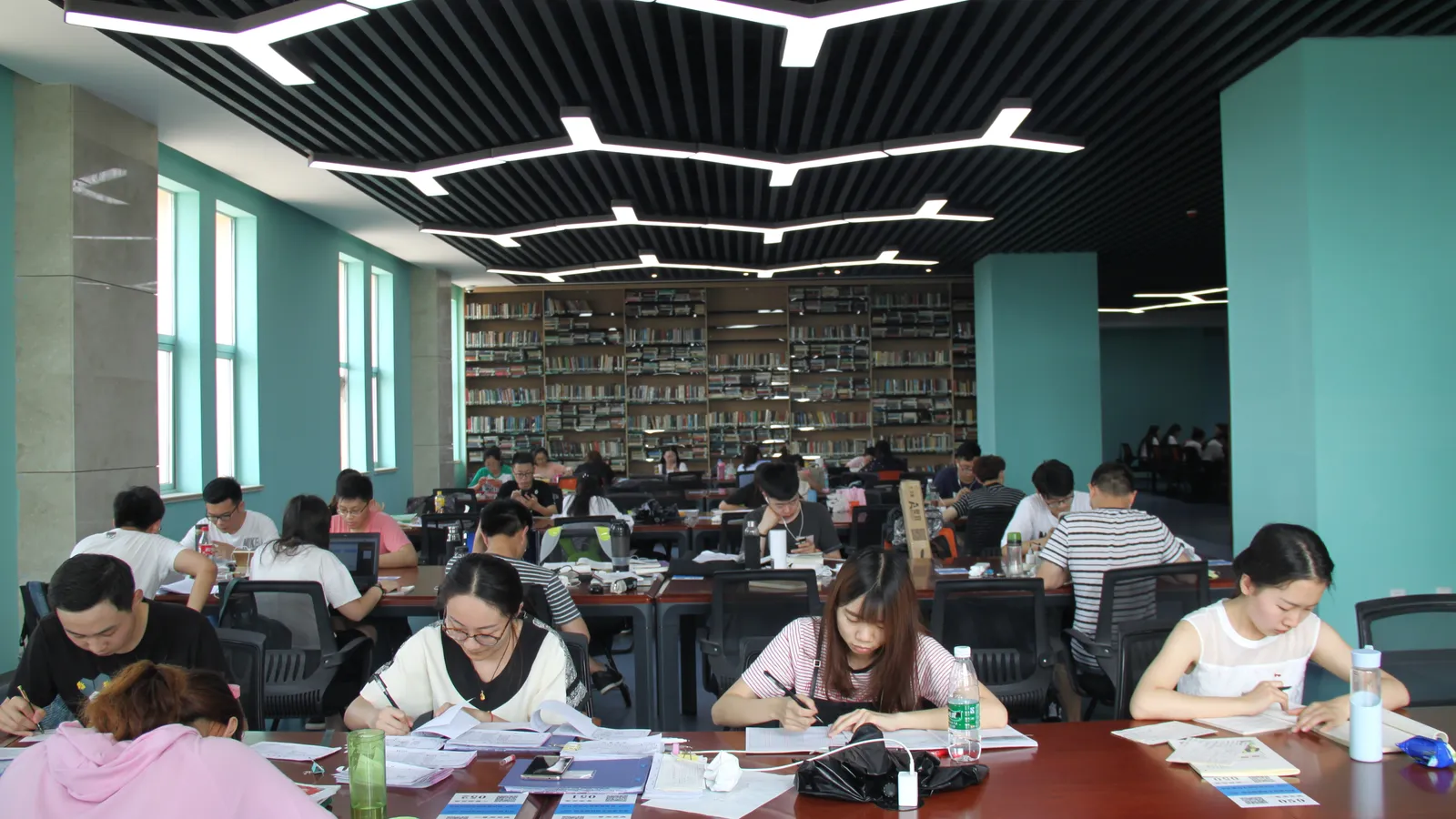 University students working through notes and textbooks at long library tables