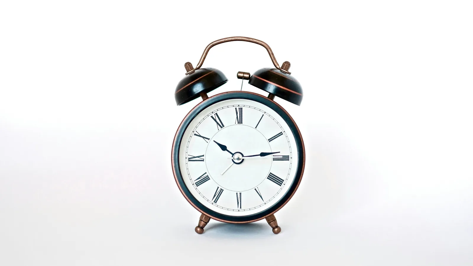 White analogue alarm clock on a white surface