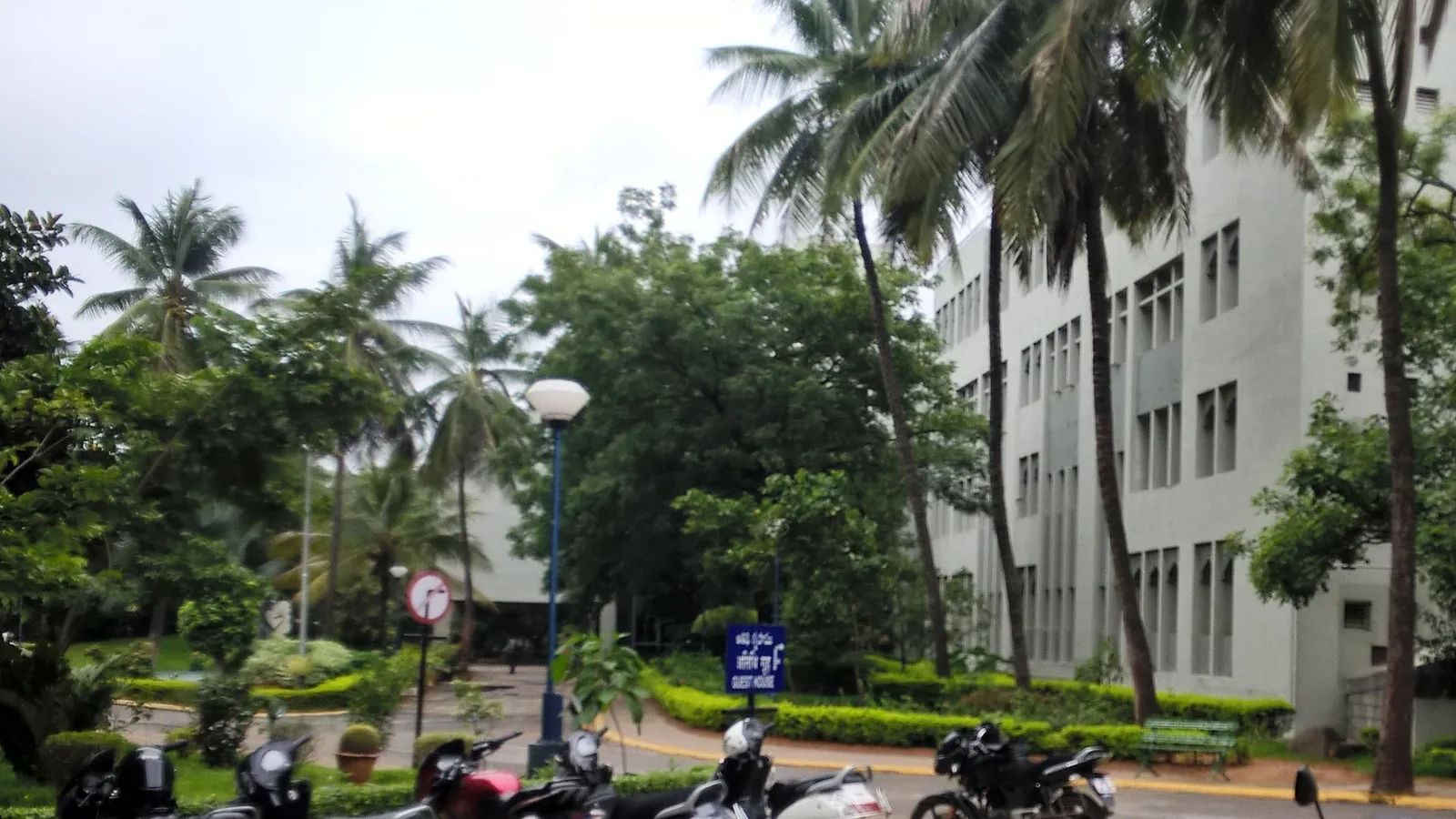 White CCMB laboratory building in Hyderabad behind palm trees and parked motorbikes