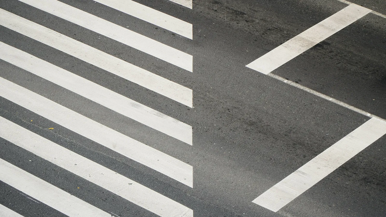 White road markings meeting at an angle on dark tarmac