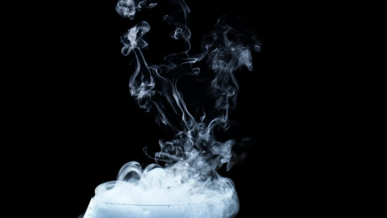 White vapour spilling and swirling against a black background