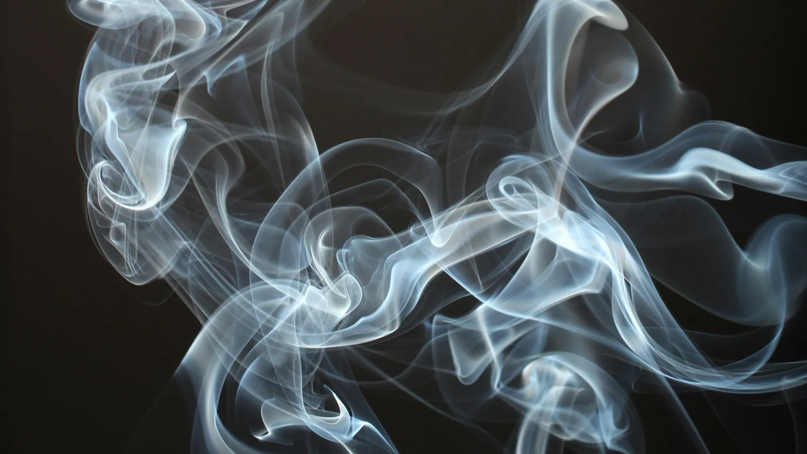 Wisps of smoke curling against a dark background