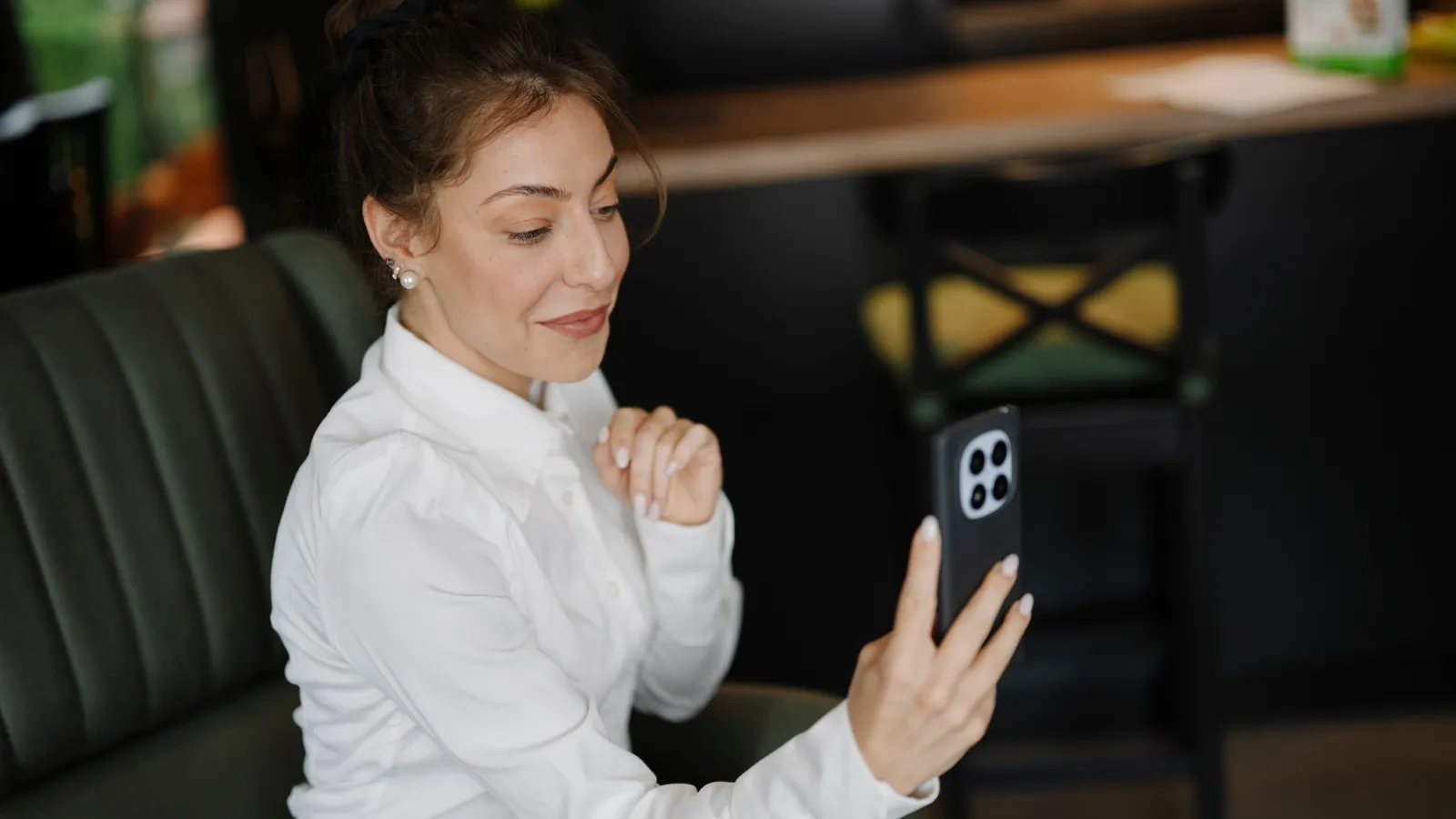 Woman in a white shirt smiling during a video call on her phone