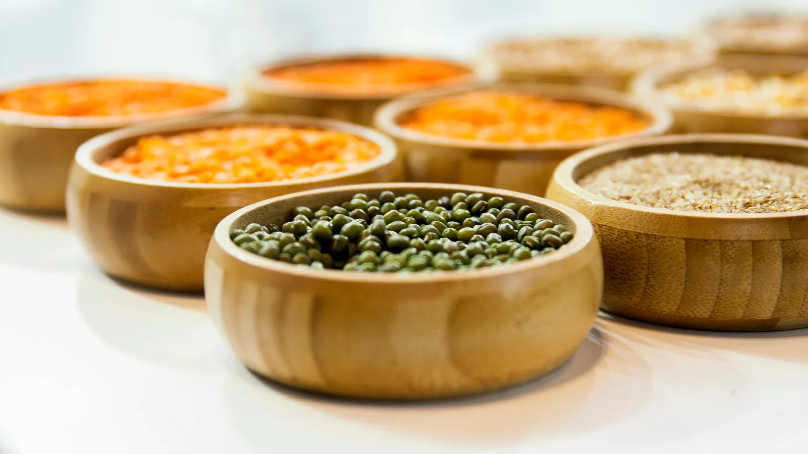 Wooden bowls filled with different lentils and pulses