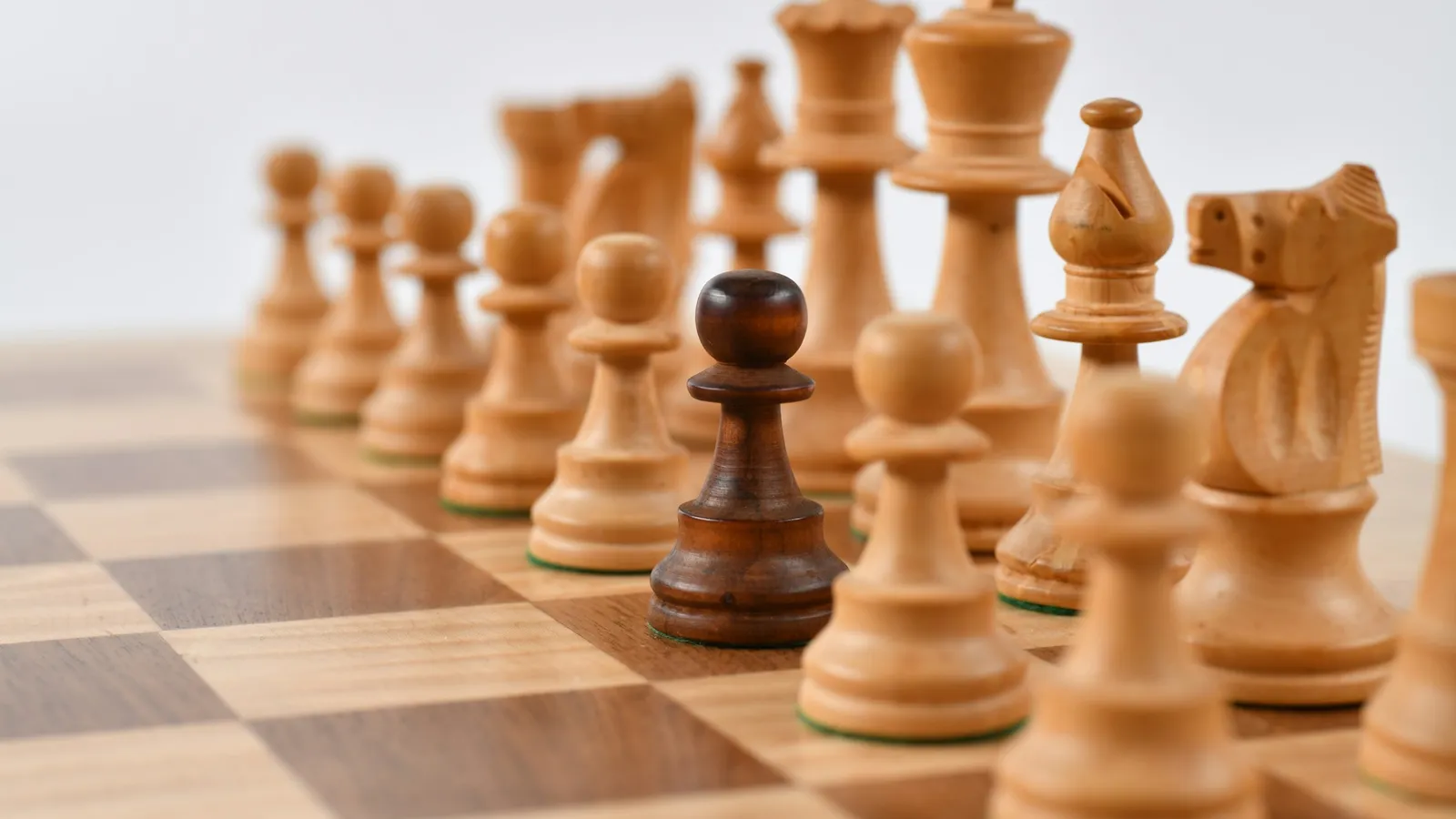Wooden chess pieces set up on a chessboard