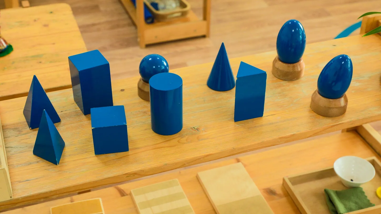 Wooden geometric solids on a classroom shelf