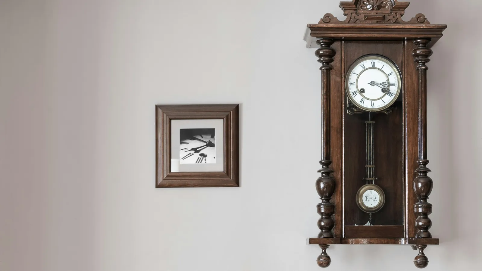 Wooden pendulum clock hanging on a white wall
