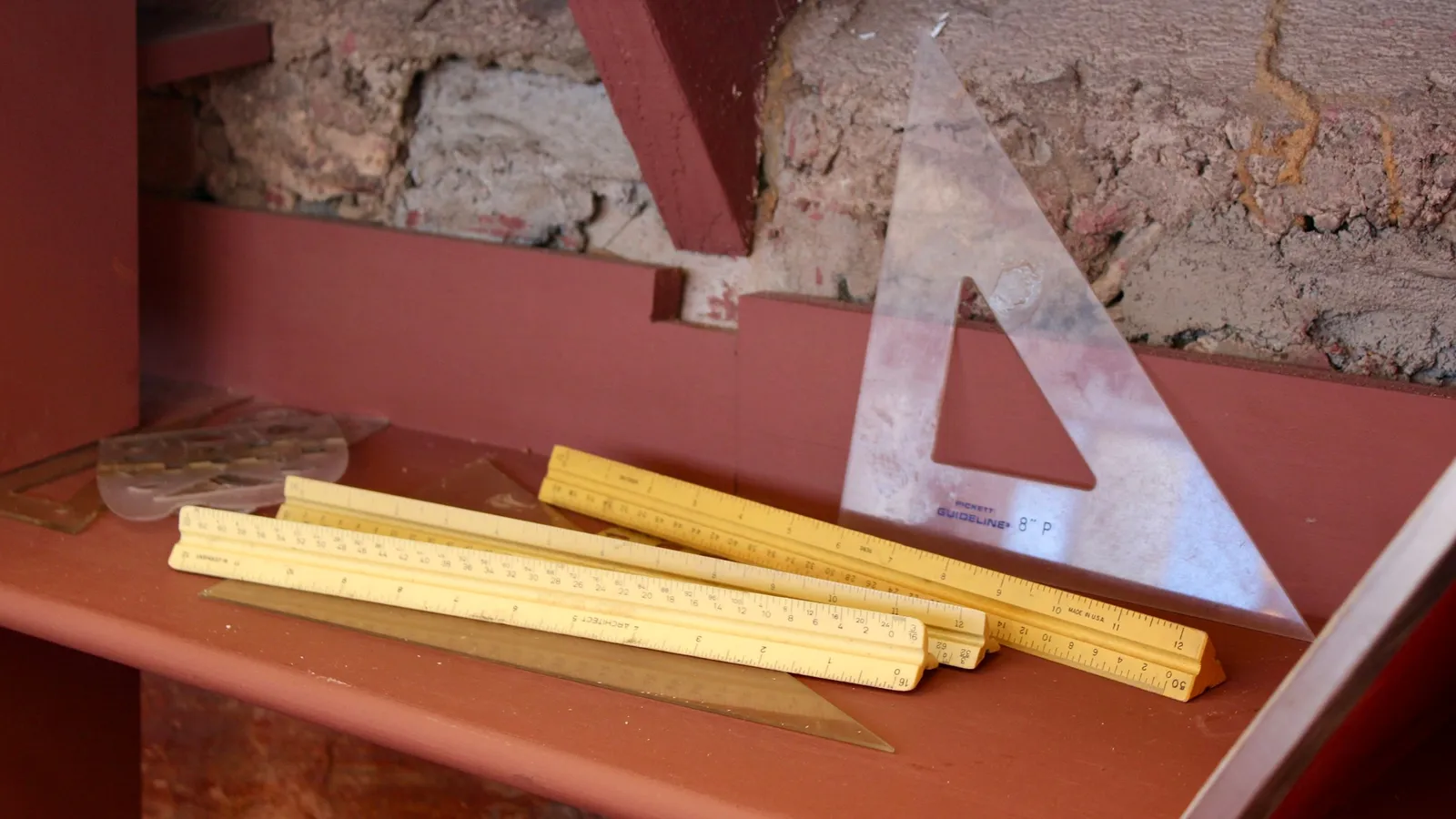 Wooden rulers and a set square on a shelf