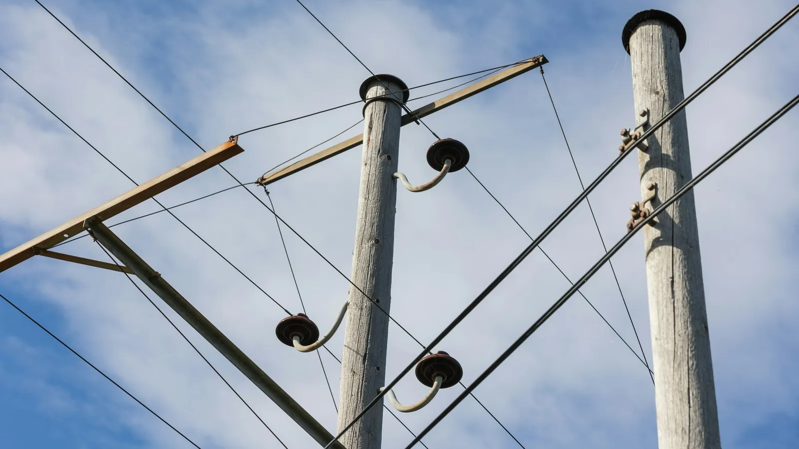 Wooden telegraph poles with glass insulators against the sky