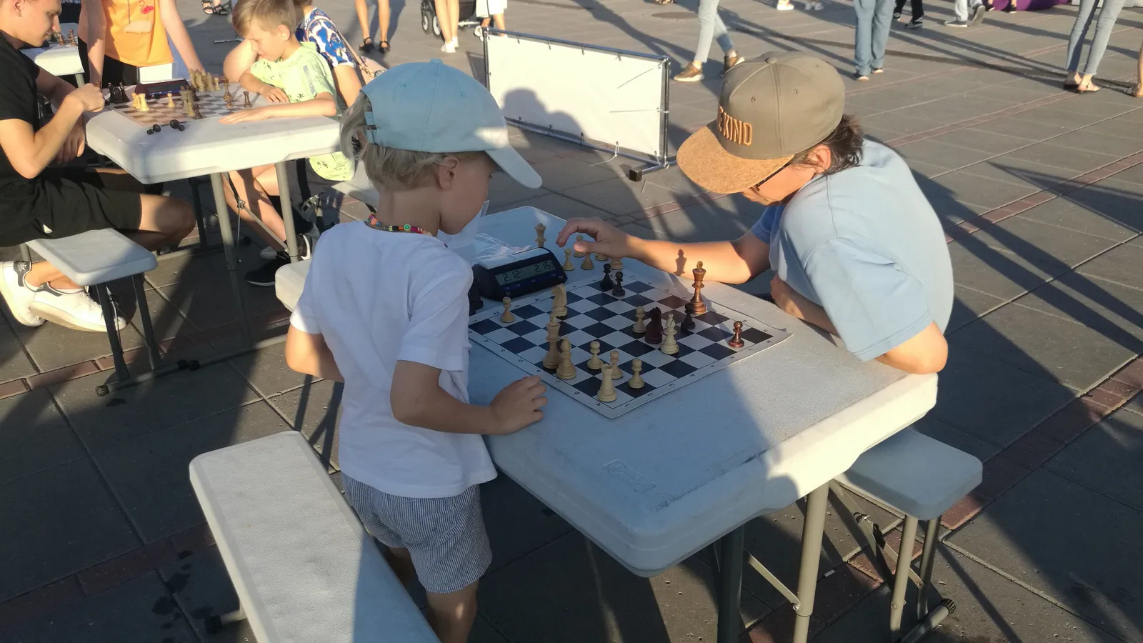 Young boy watches his opponent move a piece at an outdoor chess tournament
