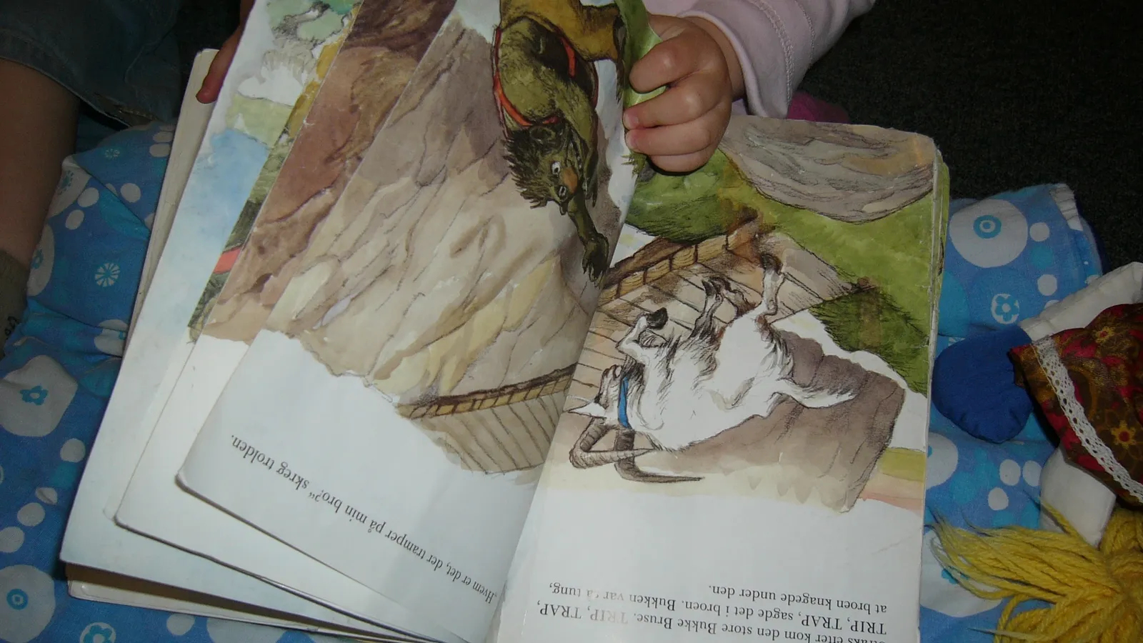 Young child's hand turning the worn pages of a well-read picture book