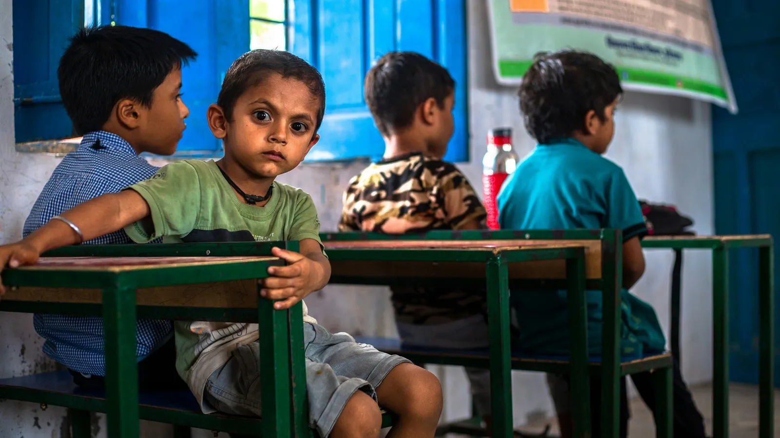 Young children sitting at desks in a village classroom