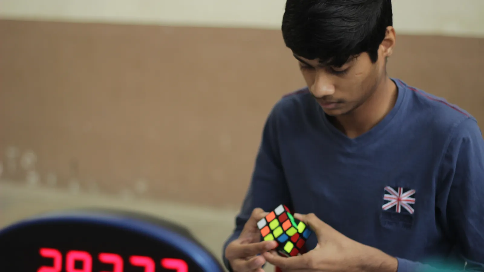 Young competitor solving a Rubik's Cube beside a timer at a Mumbai contest
