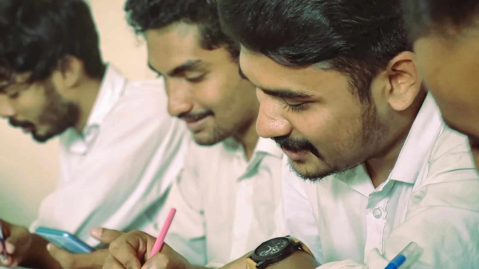 Young men sitting together at a table writing on papers