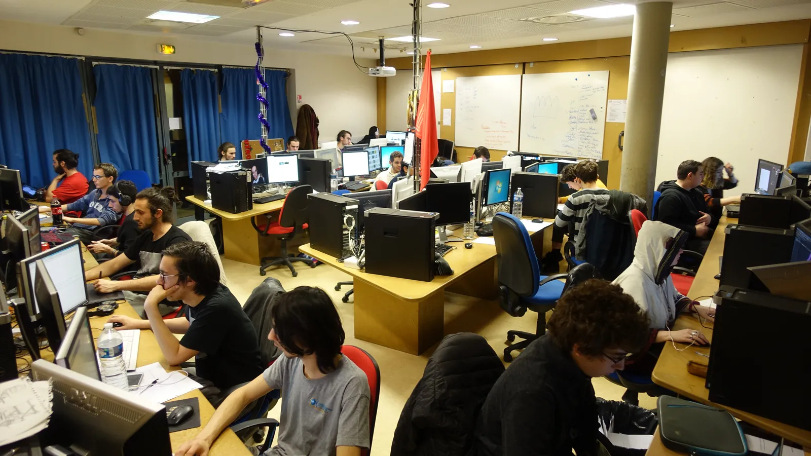 Young people working at rows of desktop computers during a game jam