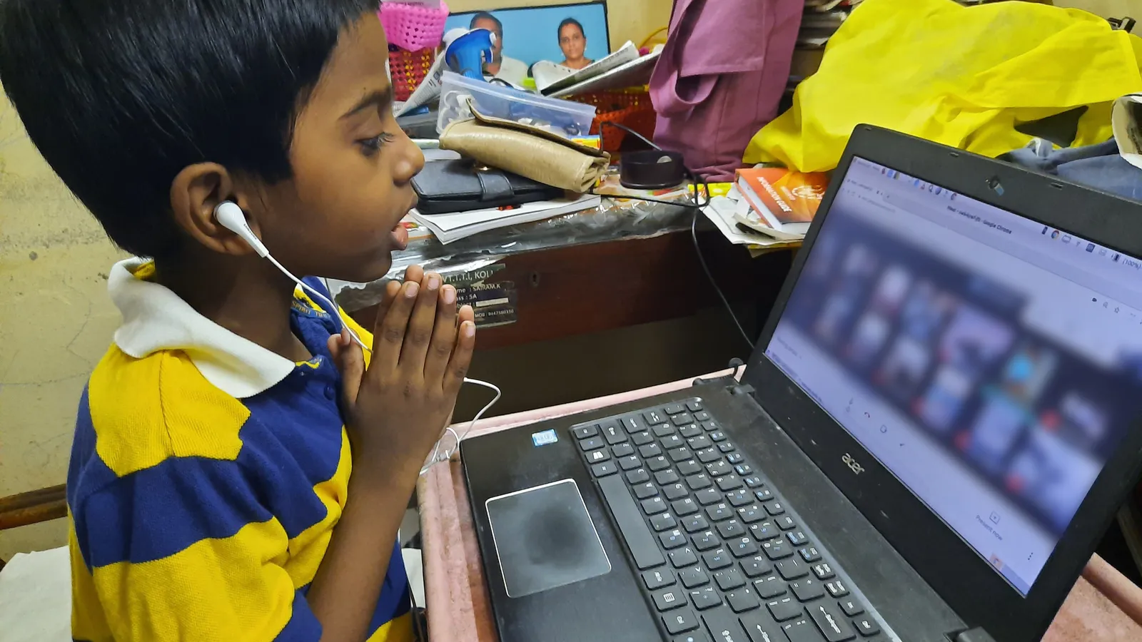 Young student with earphones and folded hands joins an online class on a laptop at home