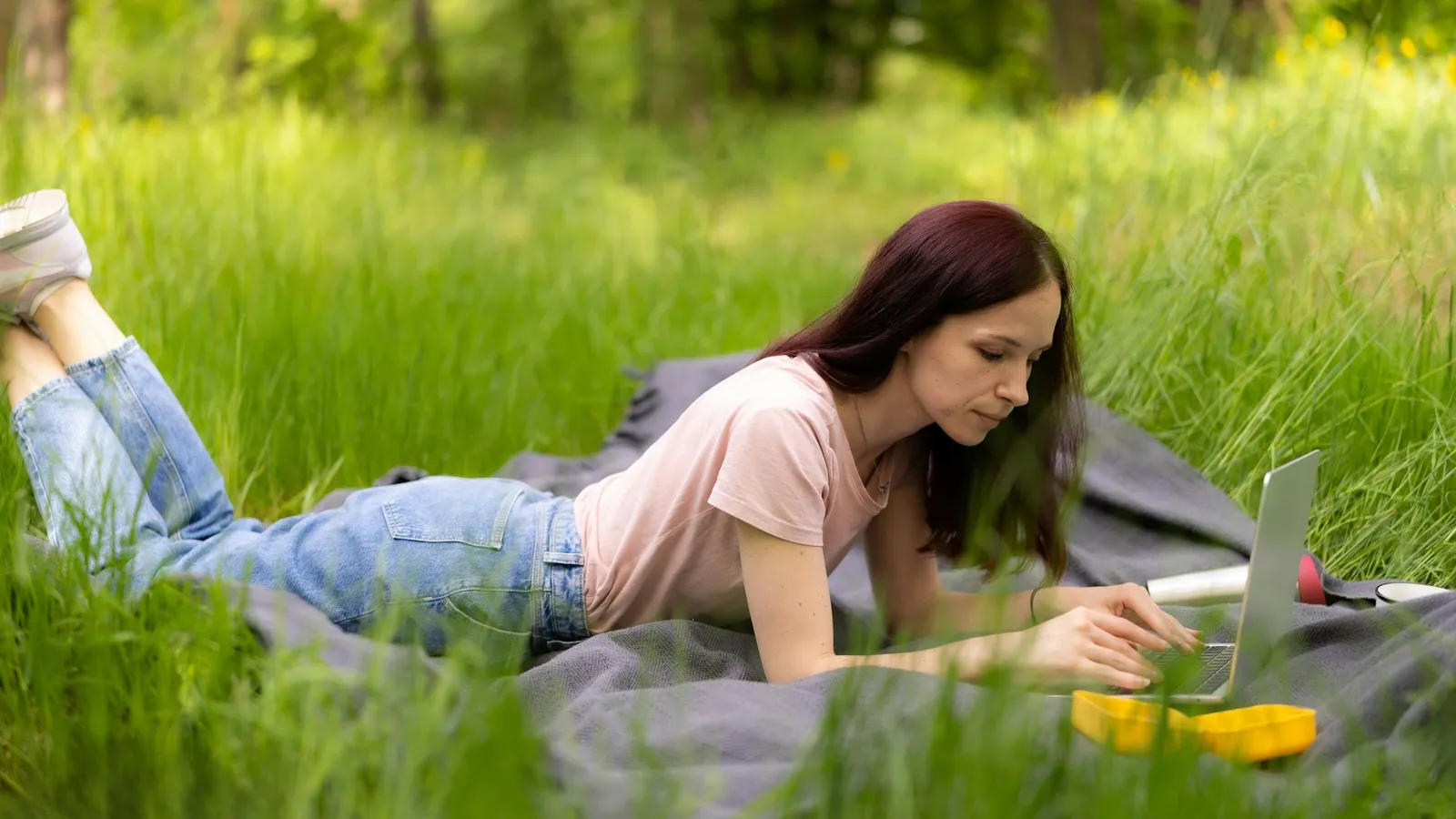 Young woman studying on the grass in summer